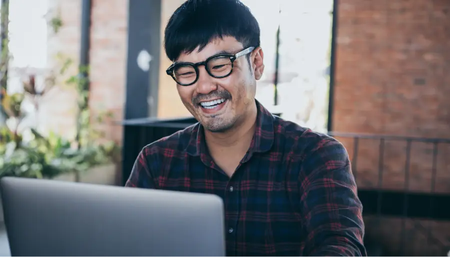 masayang lalaki na nagtatrabaho gamit ang computer na nagta-type ng laptop